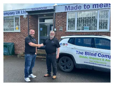 Two men shaking hands outside The Blind Company building