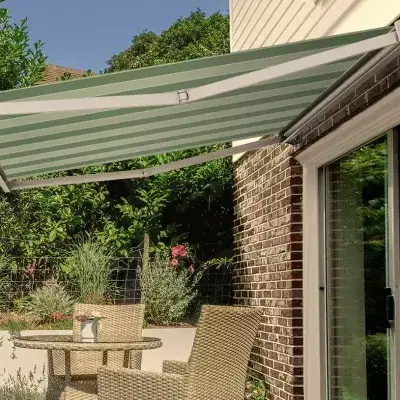 A green stripy awning covering a patio with a table and chairs