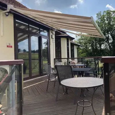 A stripy awning covering a patio with tables and chairs