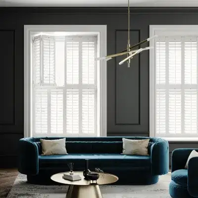 White shutters on two tall windows in an elegant sitting room